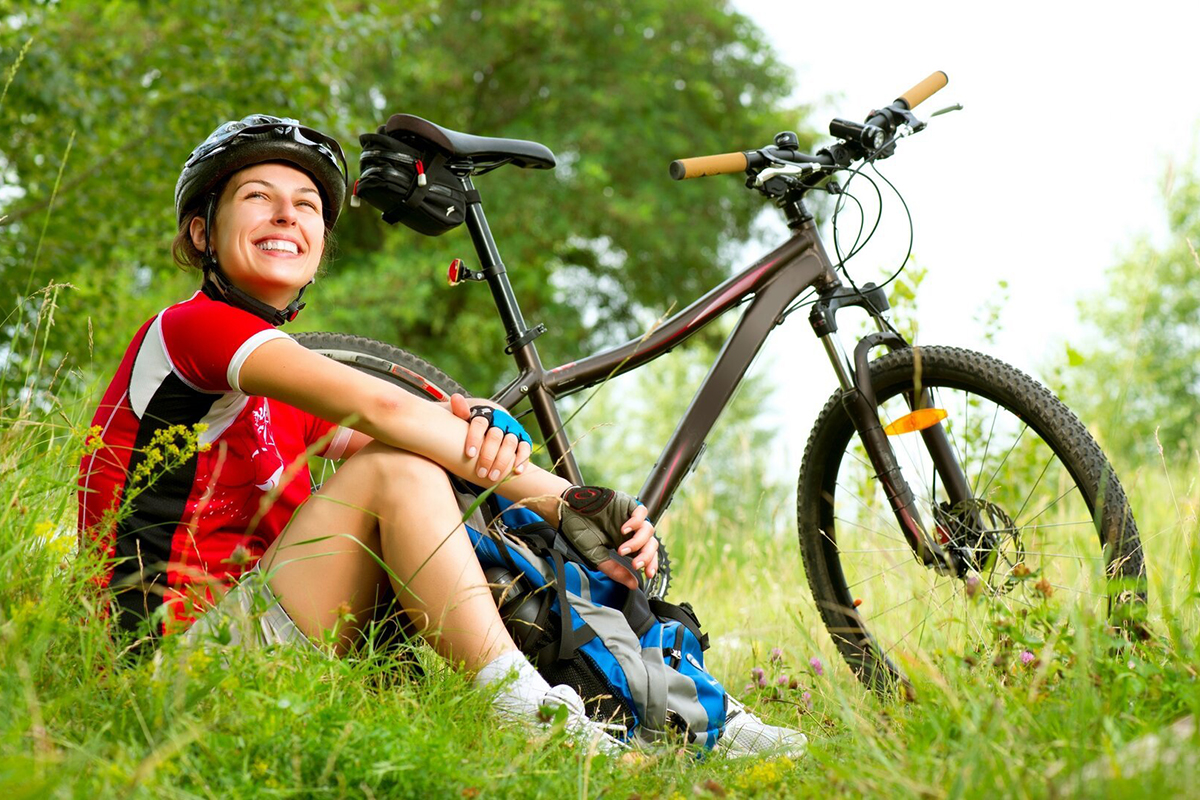 Женщина сидит на траве возле велосипеда