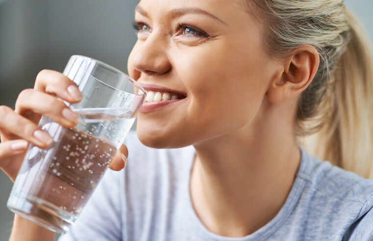 Красивая молодая женщина пьет чистую воду