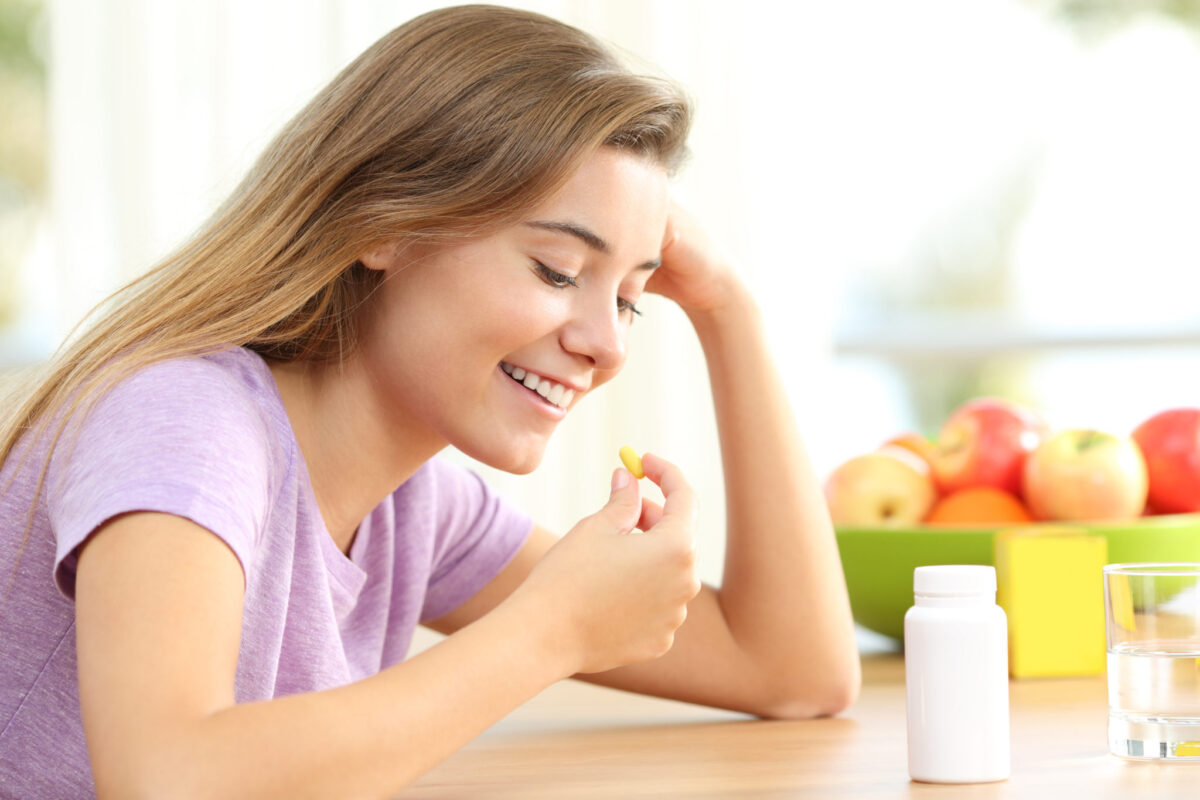 Щасливий підліток приймає таблетку вітаміну супрадин