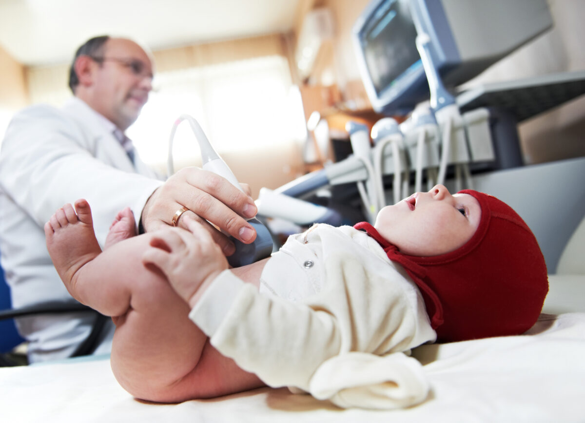 Врач с ультразвуковым оборудованием делает УЗИ сердца новорожденному